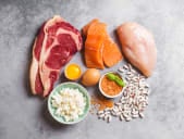 salmon, chicken, beef, eggs, and beans on a stone chopping board