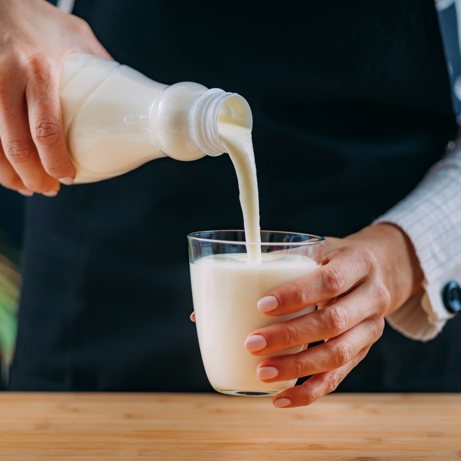 milk pouring from a glass bottle into cup