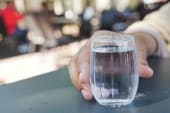 hand holding a glass of water on a table