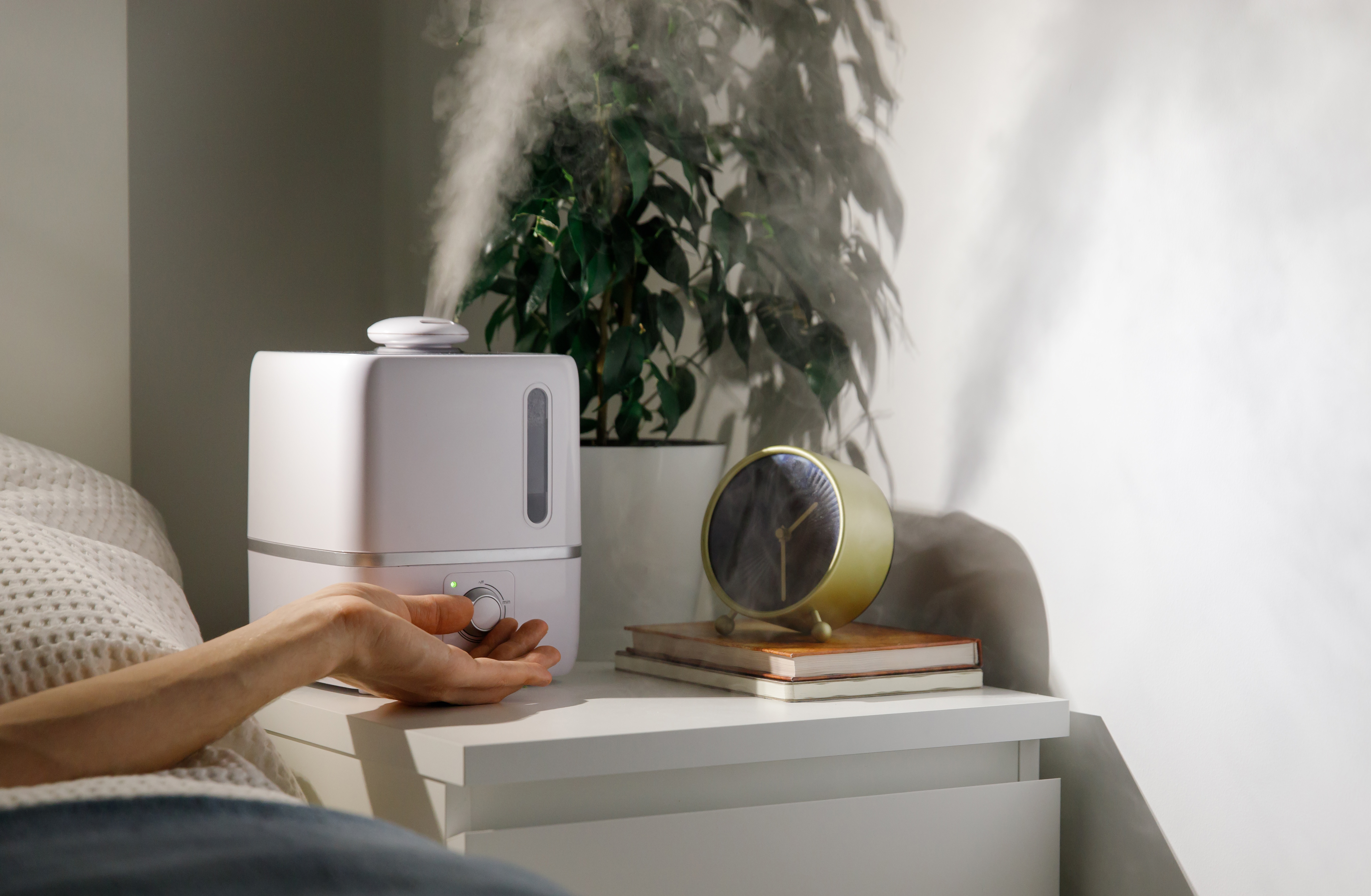person lying in bed turning on a dehumidifier