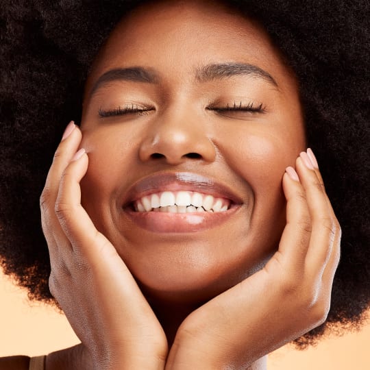 woman cupping face in hands and smiling